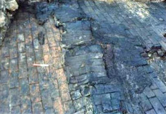  Photo    Careful excavation of the carbonised layer revealed a line of burnt barrel staves (c Museum of London)